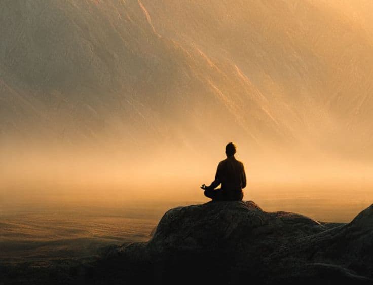 a man sitting on the rocks meditating